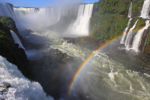 Iguazu waterfalls with rainbow on a sunny day. The largest waterfall on earth